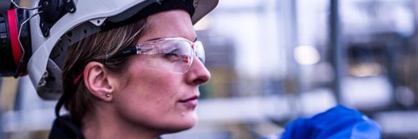 Female engineer wearing hard hat and safety glasses seen in profile